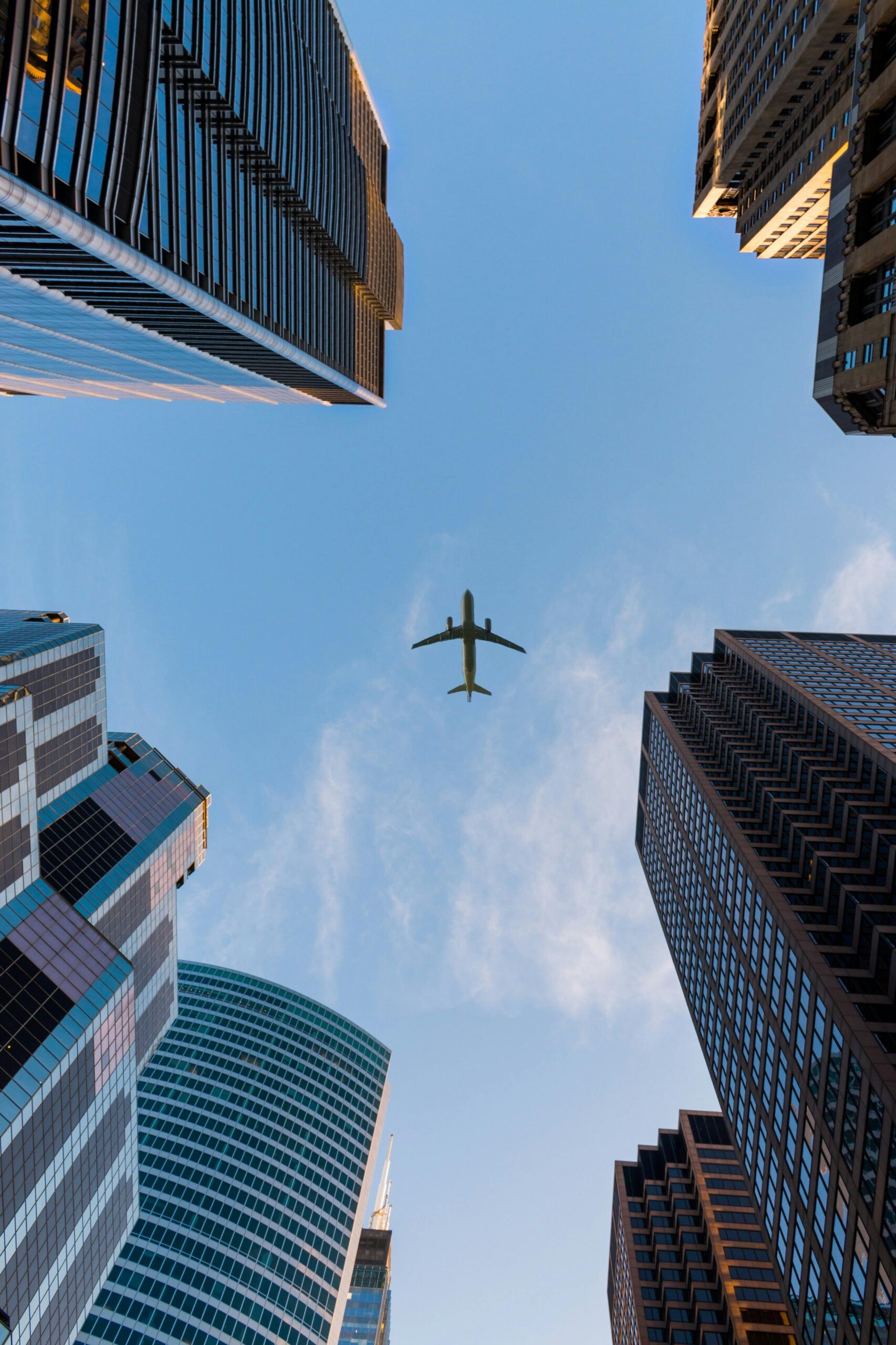 About Airplane flies over Chicago's modern skyscrapers against a clear sky, highlighting urban architecture.